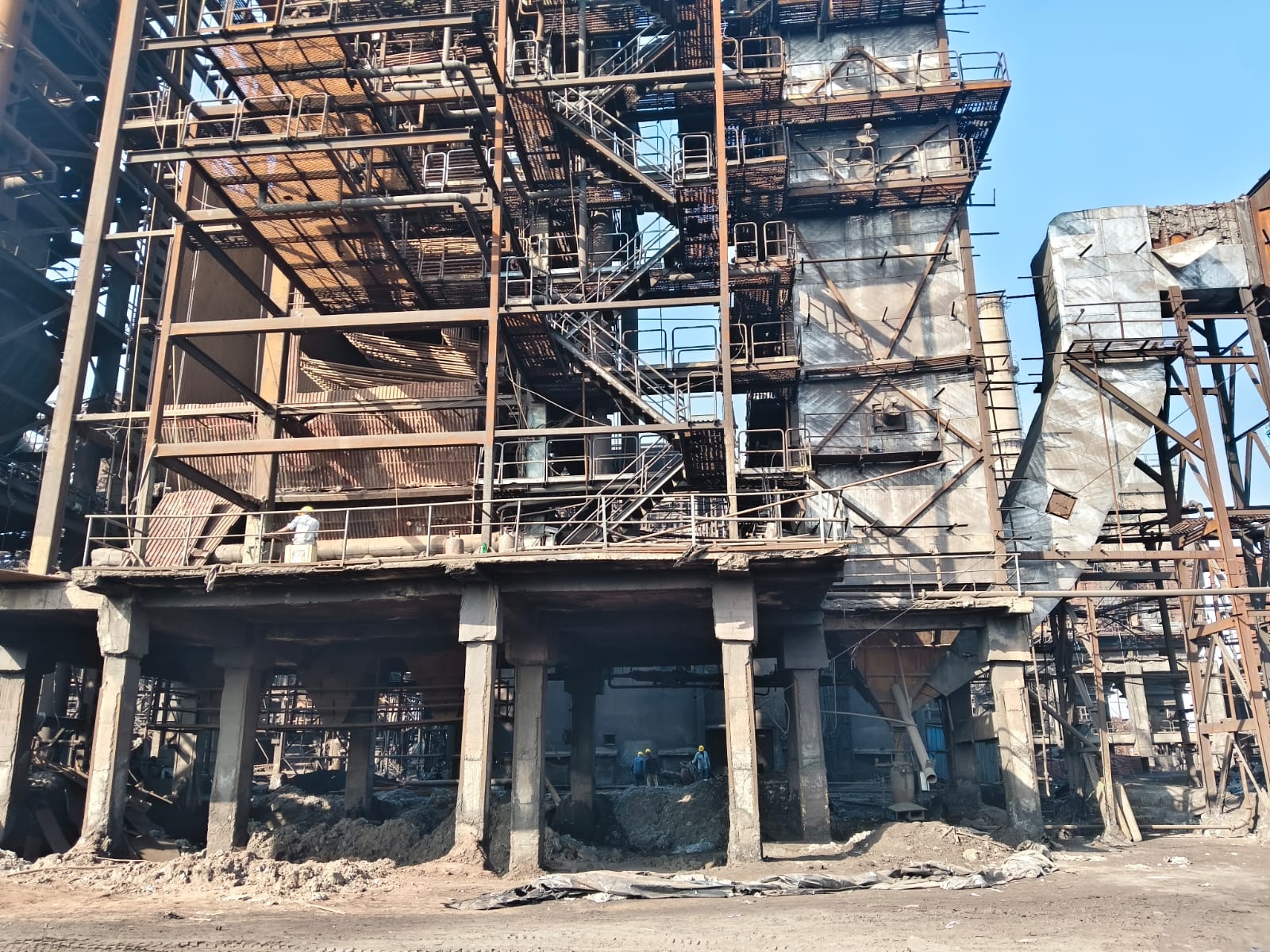 Industrial steel manufacturing facility showing large rotary kiln and multiple production units